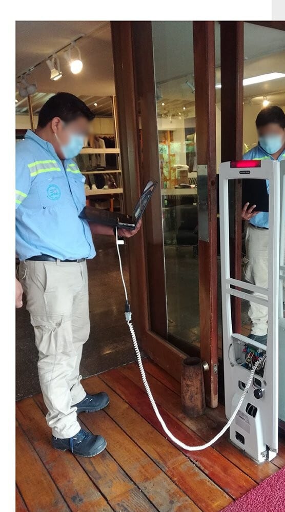 Técnico da Sensorseg fazendo manutenção em pedestal antifurto na entrada de uma loja